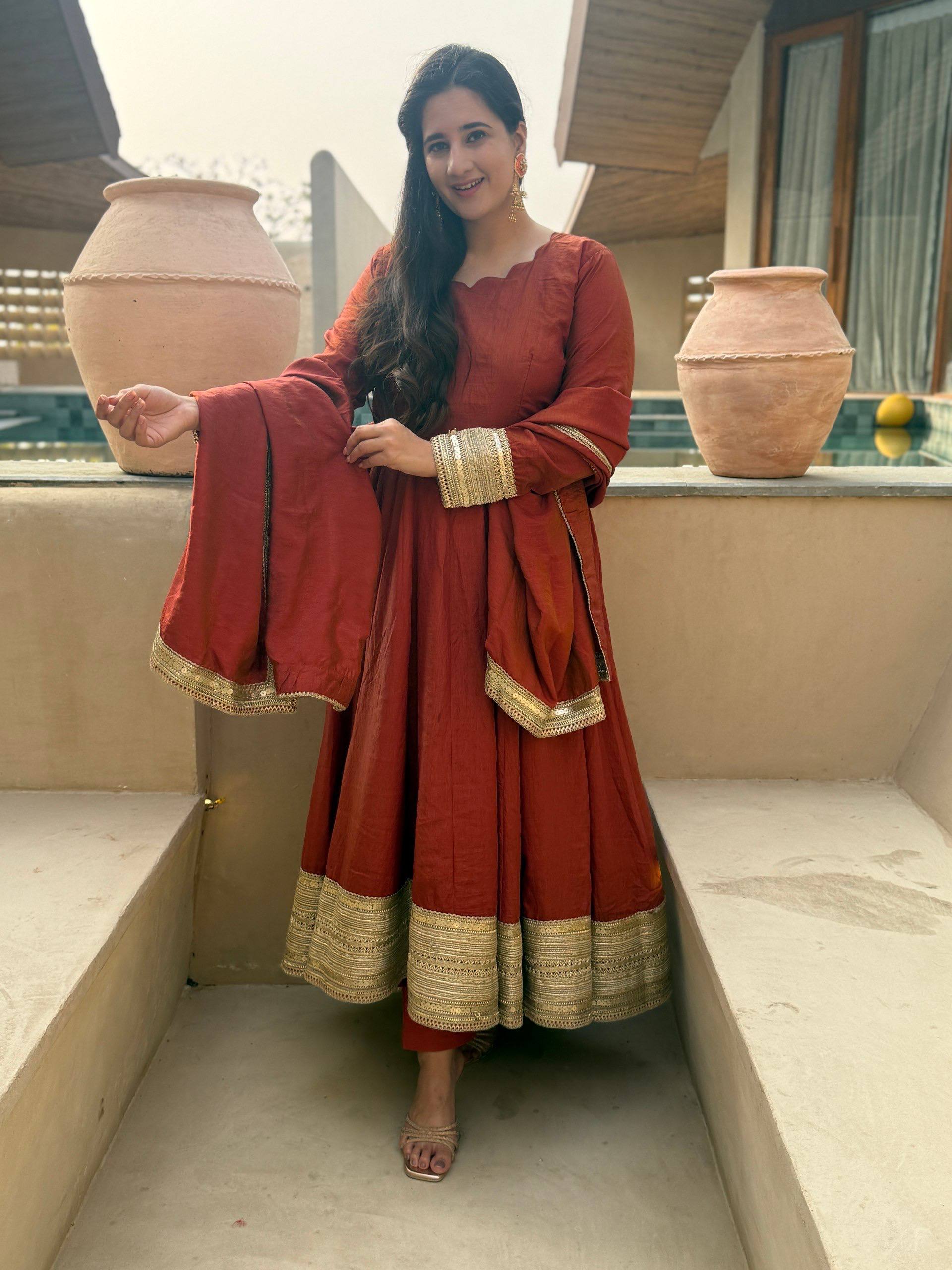 Regal Rust Orange Flared Anarkali Suit Set Featuring Ornate Gold Sequined Borders, a Scalloped Neckline, and an Elegant Tie-Up Back